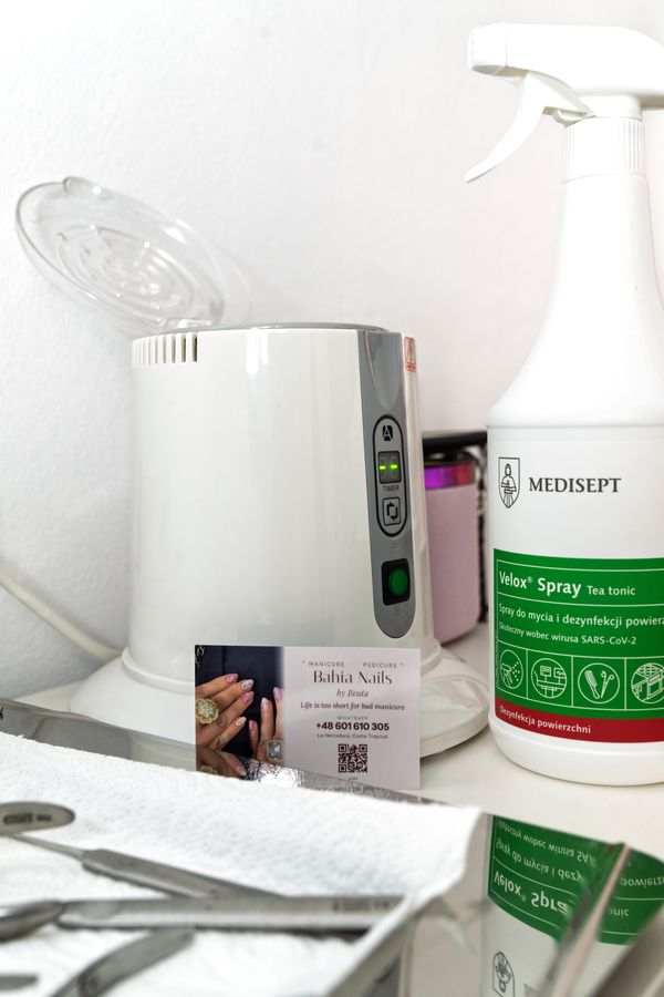 Glasperlen-Sterilisator, Desinfektionsmittel und Metallinstrumente auf sauberem Papier bei Bahia Nails
